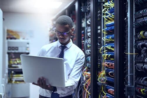 IT professional on a laptop in a server room